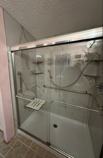 Zero-threshold walk-in shower with marble walls, grab bars, and fold-down seat