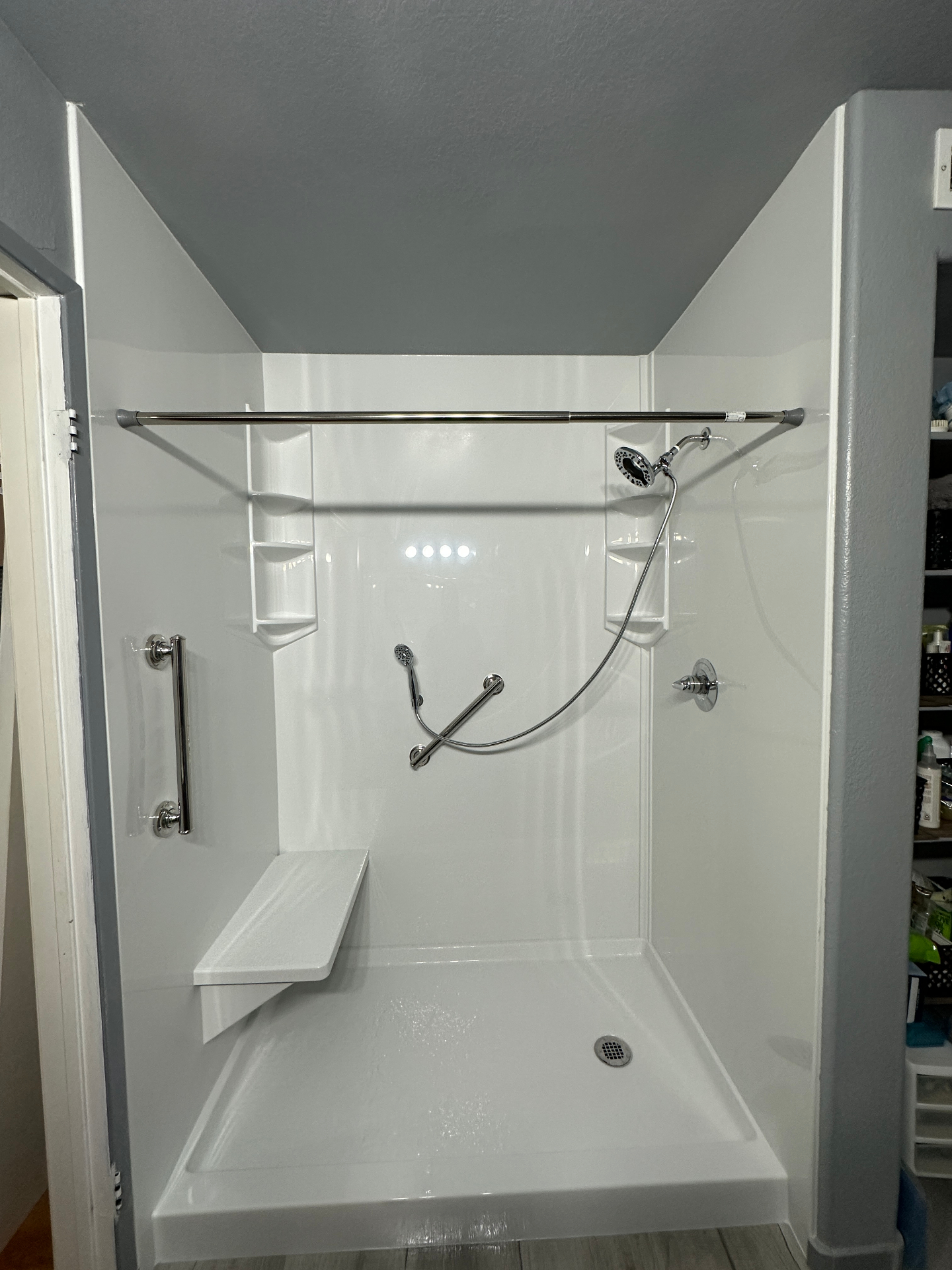 Roll-in accessible shower with grab bars, built-in bench seat, and handheld showerhead