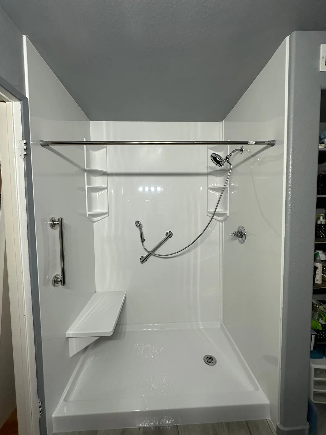 Accessible shower with handheld showerhead on adjustable slide bar and grab bars