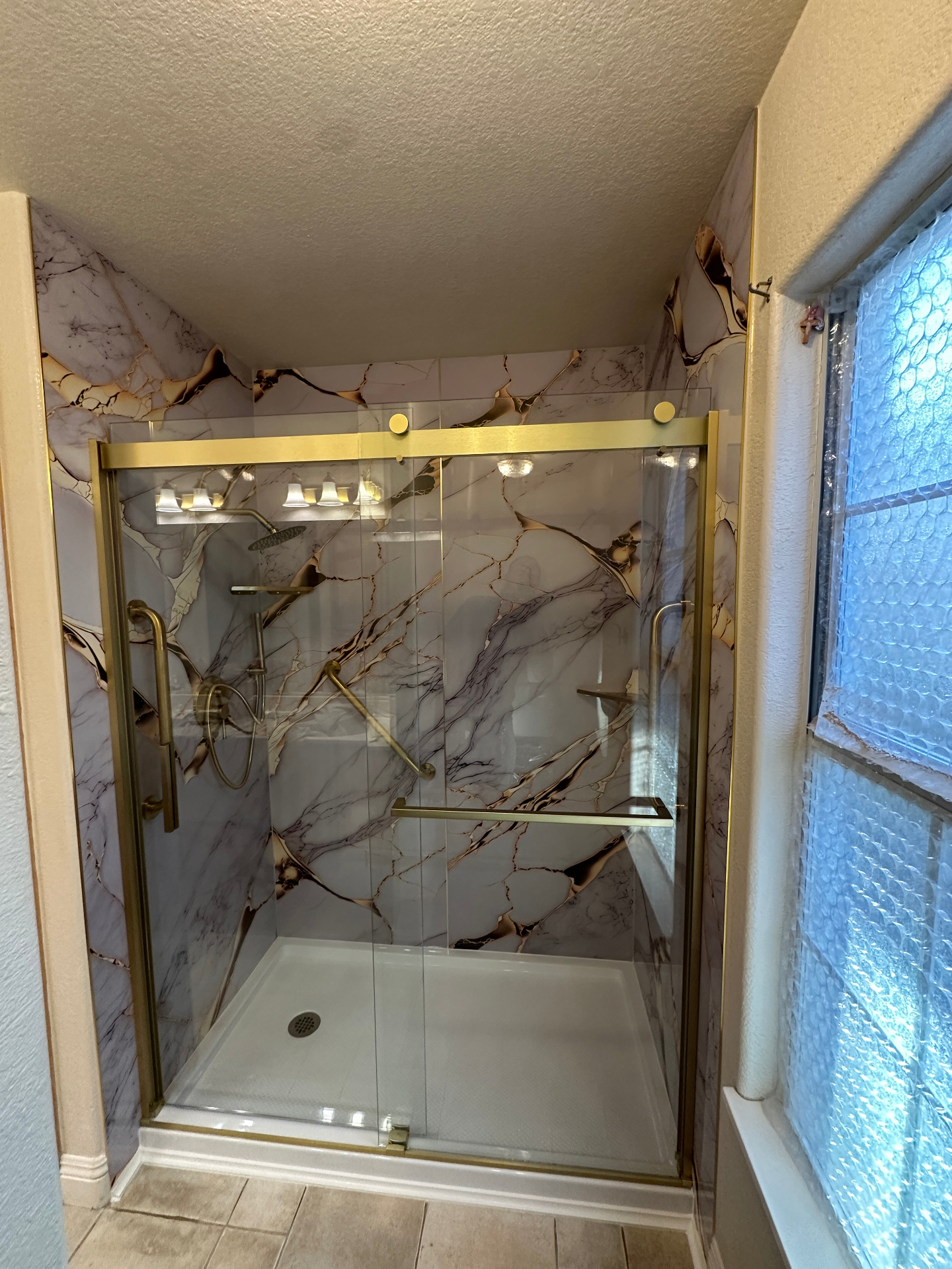 Curbless walk-in shower with gold fixtures and marble wall panels